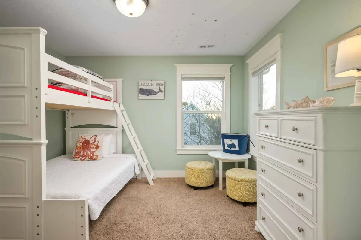 A playful interior scene with a bunk bed, a dressing table, cheerful artwork on the walls, and a window offering a pleasant view. The room is designed for fun, relaxation, and memorable sleepovers.