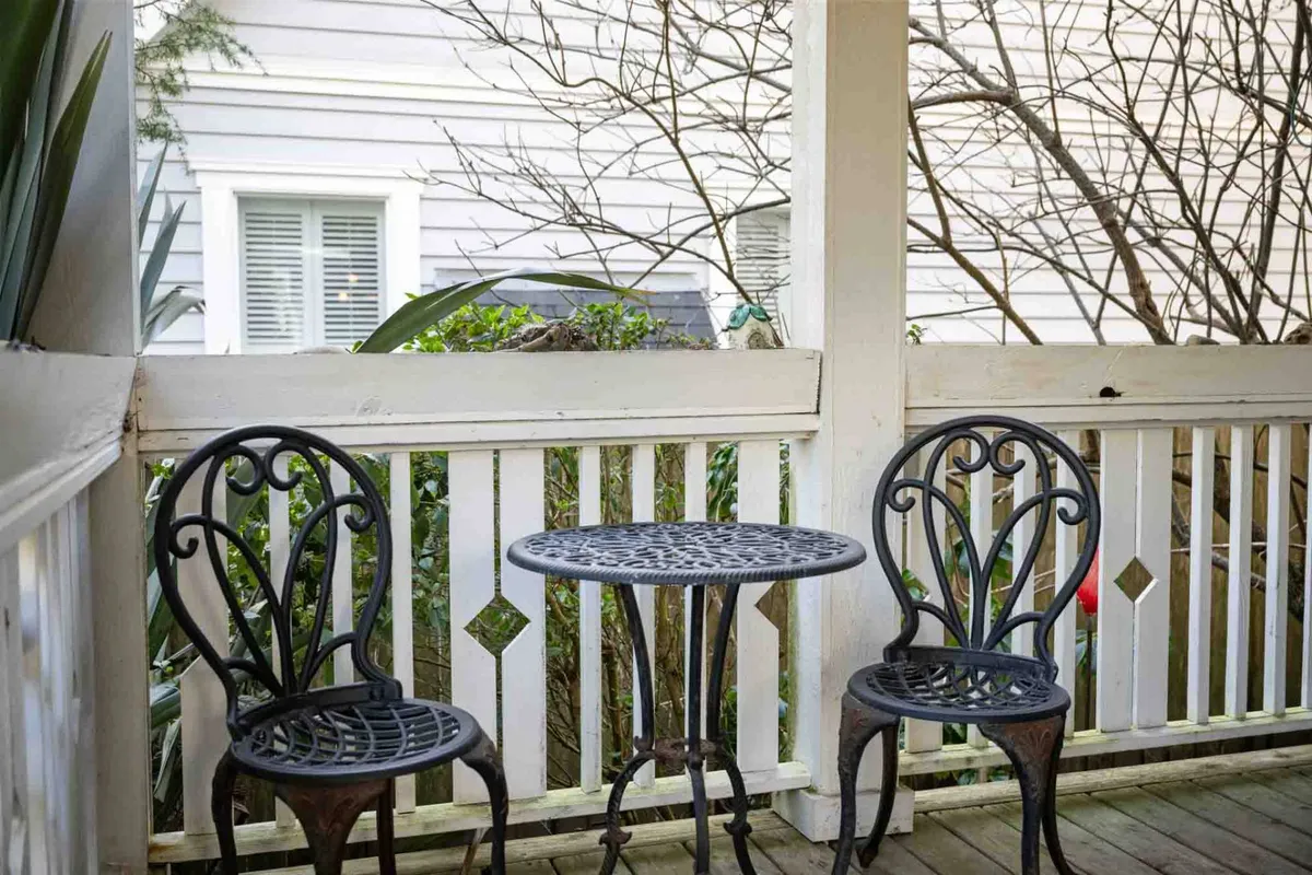 A cozy exterior seating area featuring wrought iron chairs and a round table on a small patio, bordered by a decorative railing. The setting is intimate—designed for quiet reflection, morning sunrises, or sharing stories with loved ones.